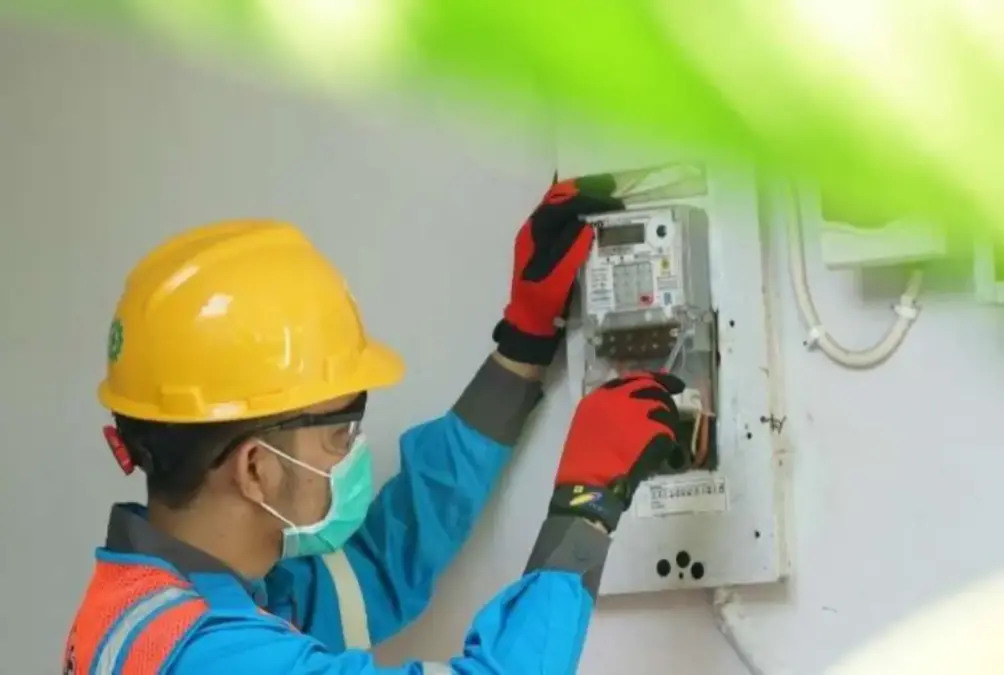 Terbaru! Tarif Listrik Desember 2025 Dipastikan Tetap, Cek Rincian Harga per kWh Petugas PLN sedang mengecek meteran listrik